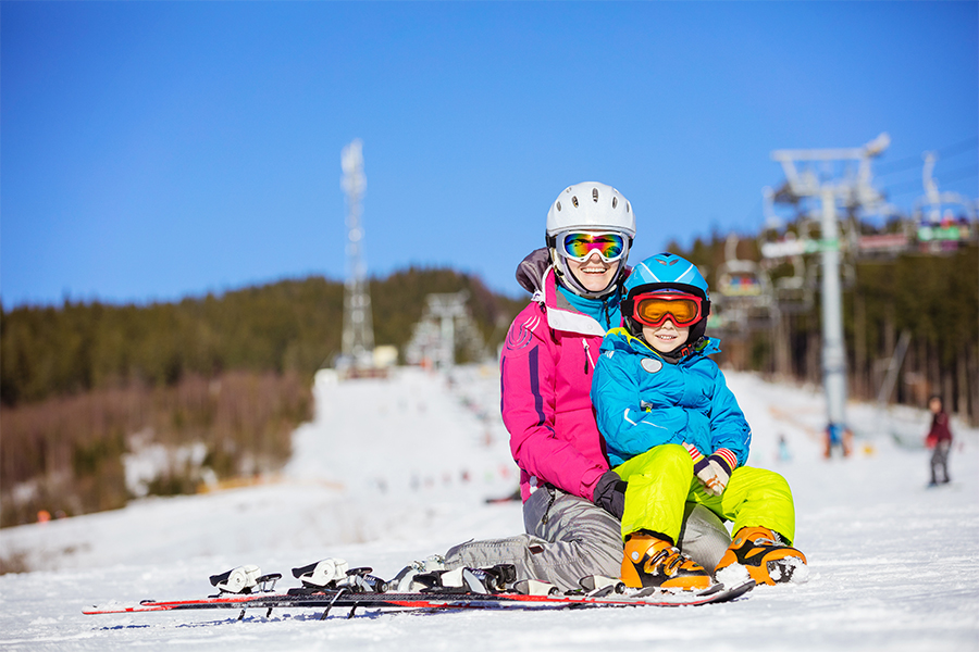 cheerful-mother-and-son-resting-on-ski-slope-PFHTTKKl