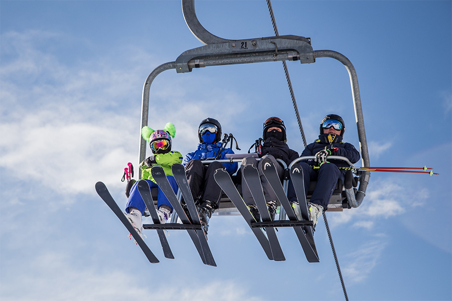 ski-lift-with-four-skiers-in-front-of-the-blue-sky-67FKAH7c